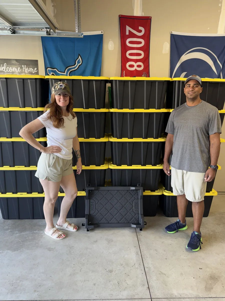 Erica and Tyler standing beside stacks of Tubby Tyler moving totes